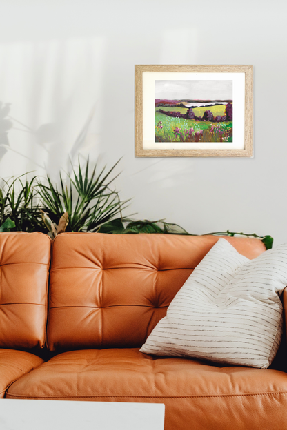 Framed landscape painting on a wall above an orange leather sofa with decorative pillows. Original artwork Bay by Teri Stephens