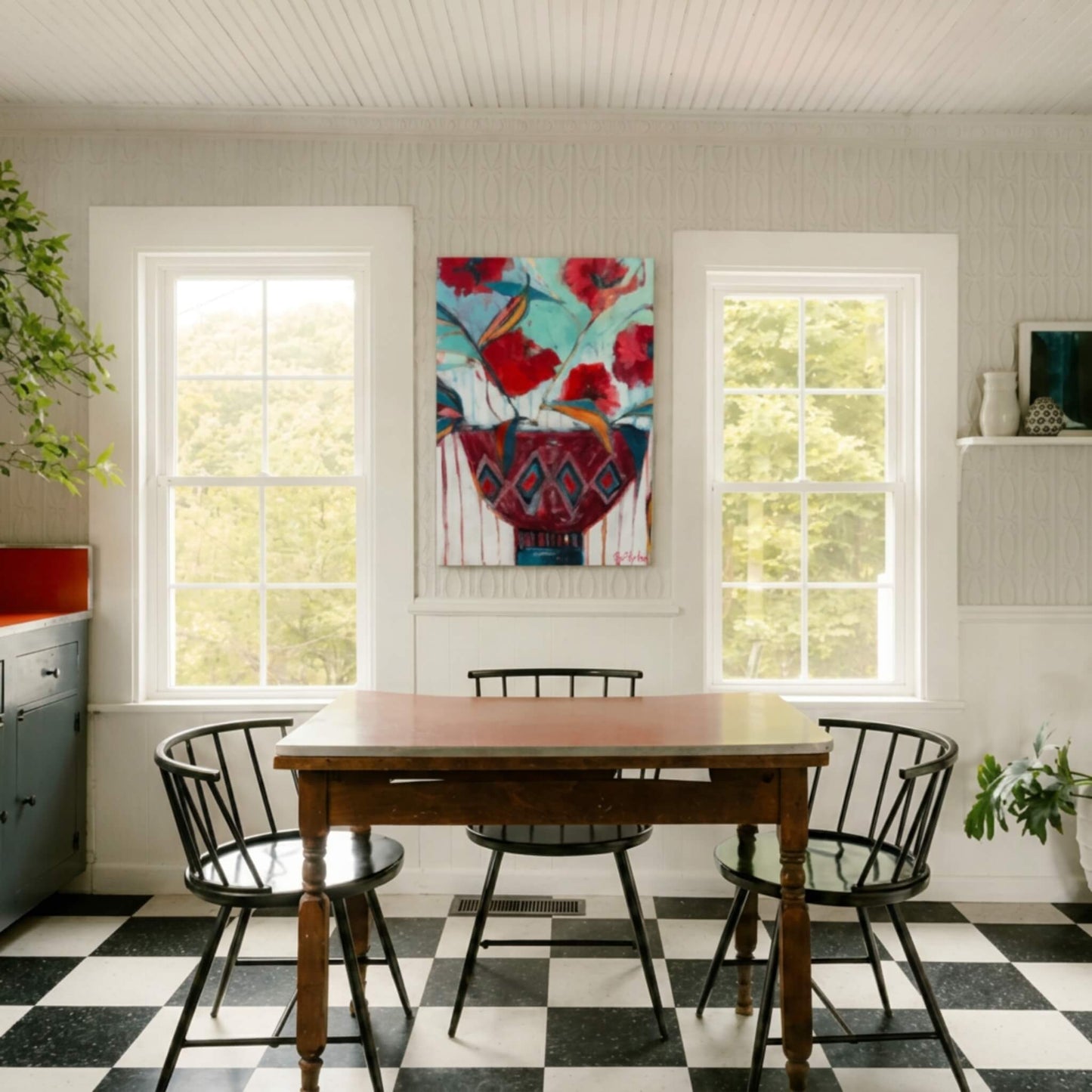 Contemporary dining room featuring an original acrylic floral bowl painting by Tennessee artist Teri Stephens displayed between two windows above a farmhouse table.