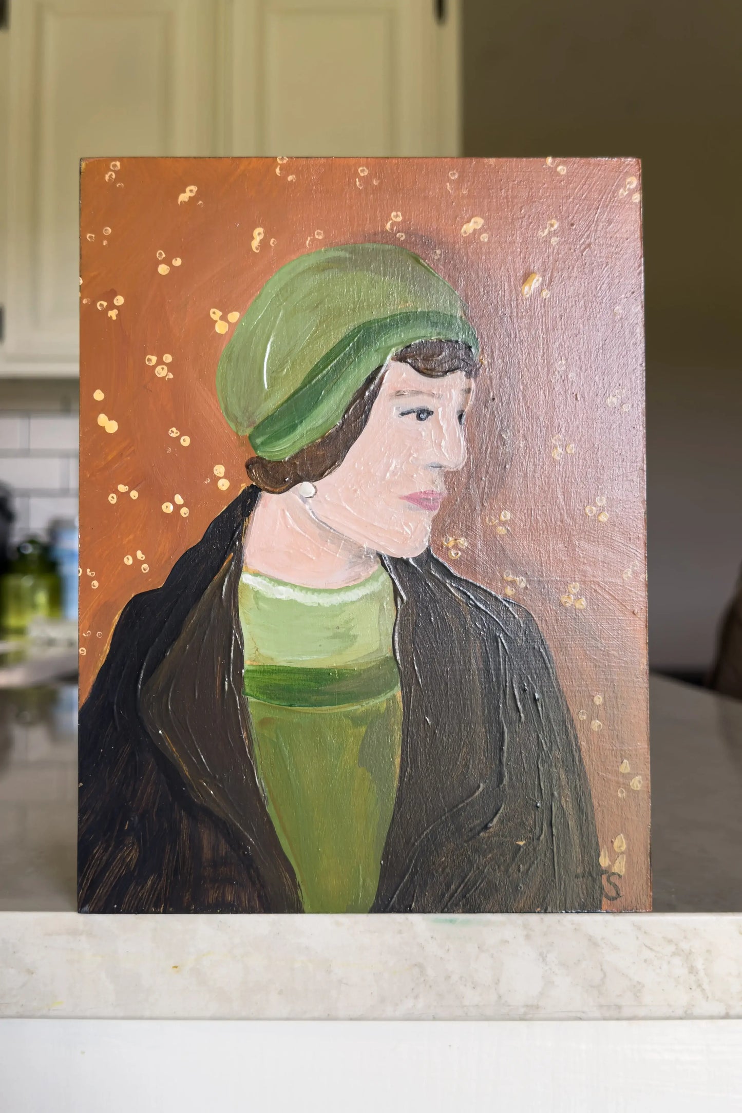 Portrait painting of a woman with a green headscarf on a wooden surface.