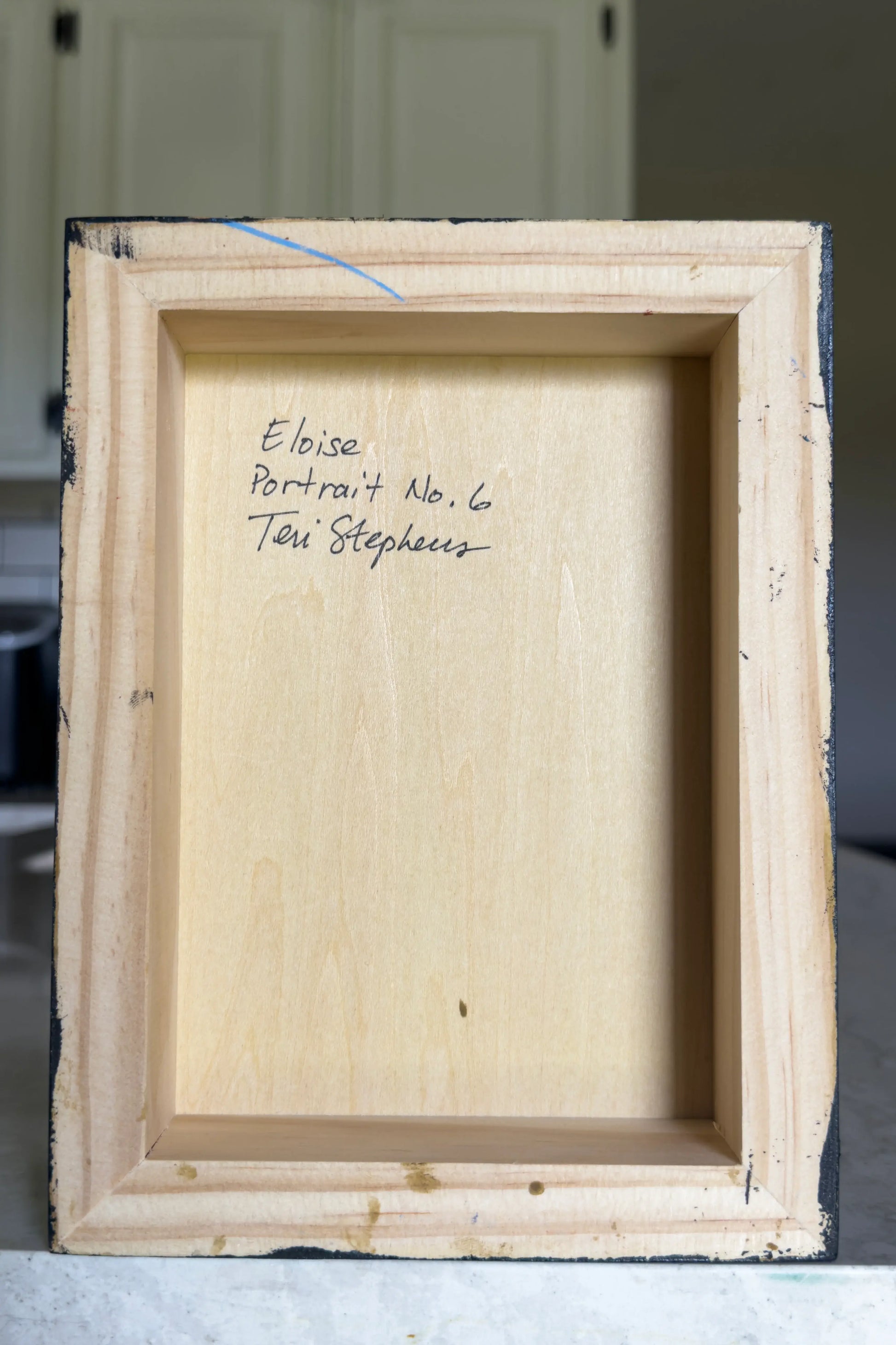 Back of a wooden picture frame with text on a neutral background