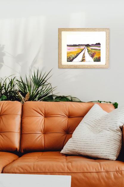 Framed artwork, original painting titled "Fields" by Teri Stephens, above an orange leather sofa with a plant in the background