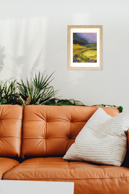 Framed painting of a landscape above an orange leather sofa with decorative pillows. Artwork titled "Glen" by artist Teri Stephens