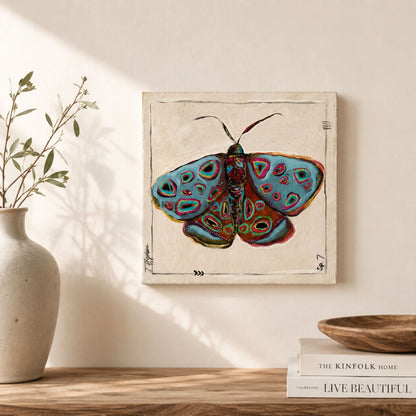 Hover is an original painting of a moth on canvas, featuring shades of soothing blue, rust and pops of green and pink.