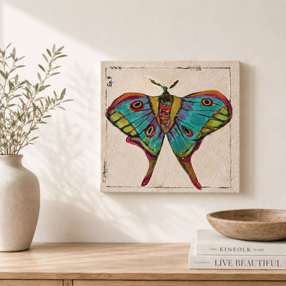 Kismet is an original painting of a luna moth, styled in bold colors of blue, teal, green and pink. 