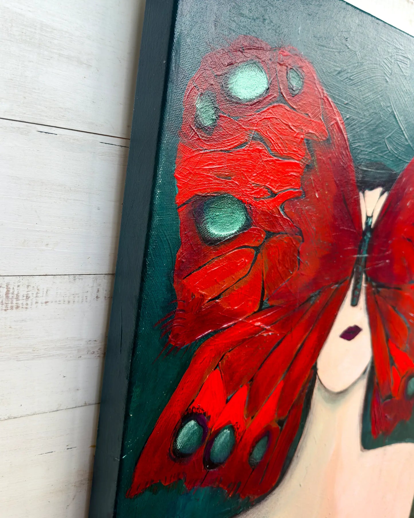 Painting of a red butterfly with green spots on a black background