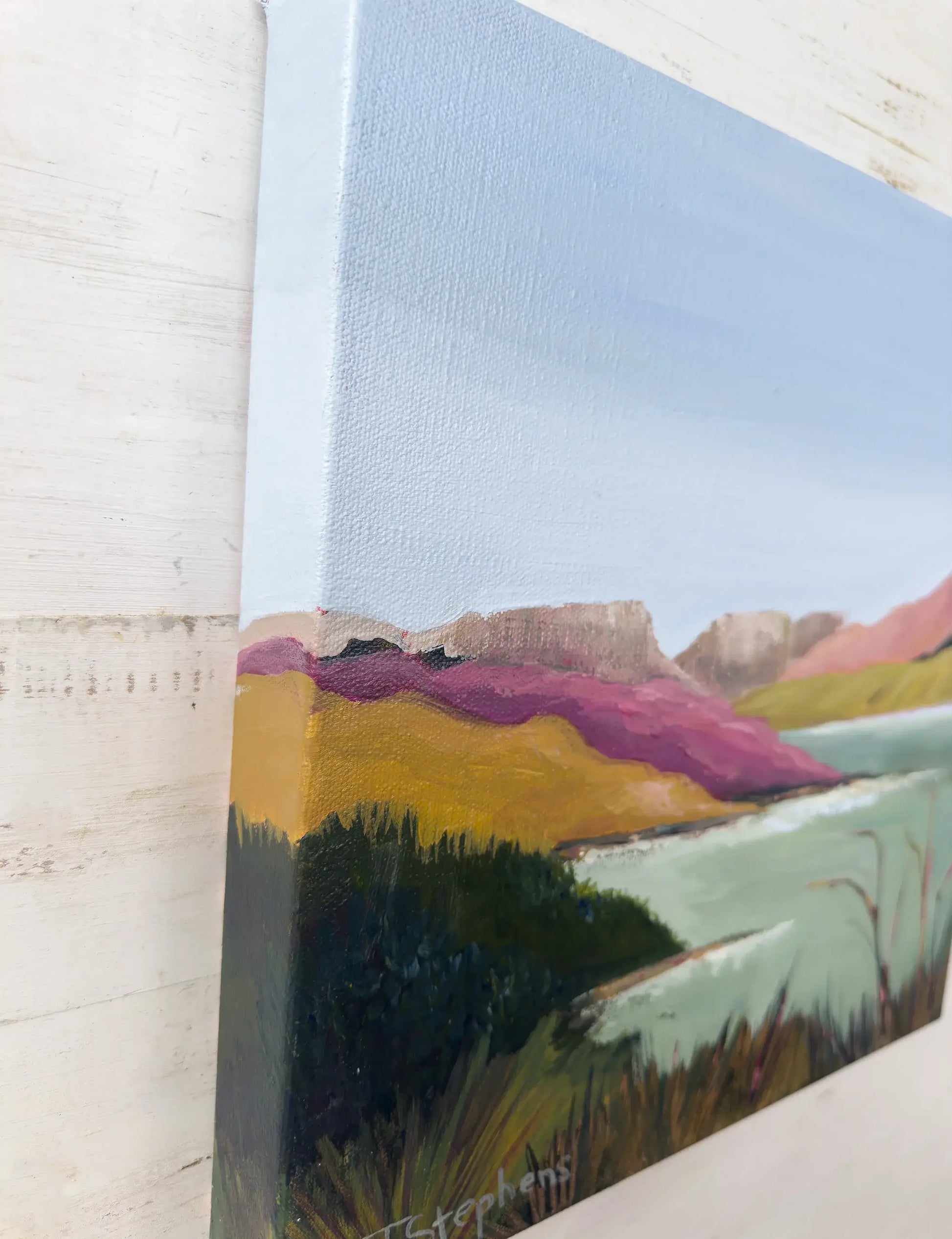 Close-up of a landscape painting with a textured wall background, angled view of  original painting titled "Reservoir" by Teri Stephens