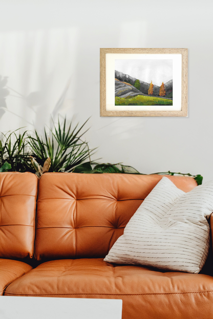 Framed landscape painting above an orange leather sofa with a plant in the corner. Original painting titled Ridge by Tennessee artist Teri Stephens