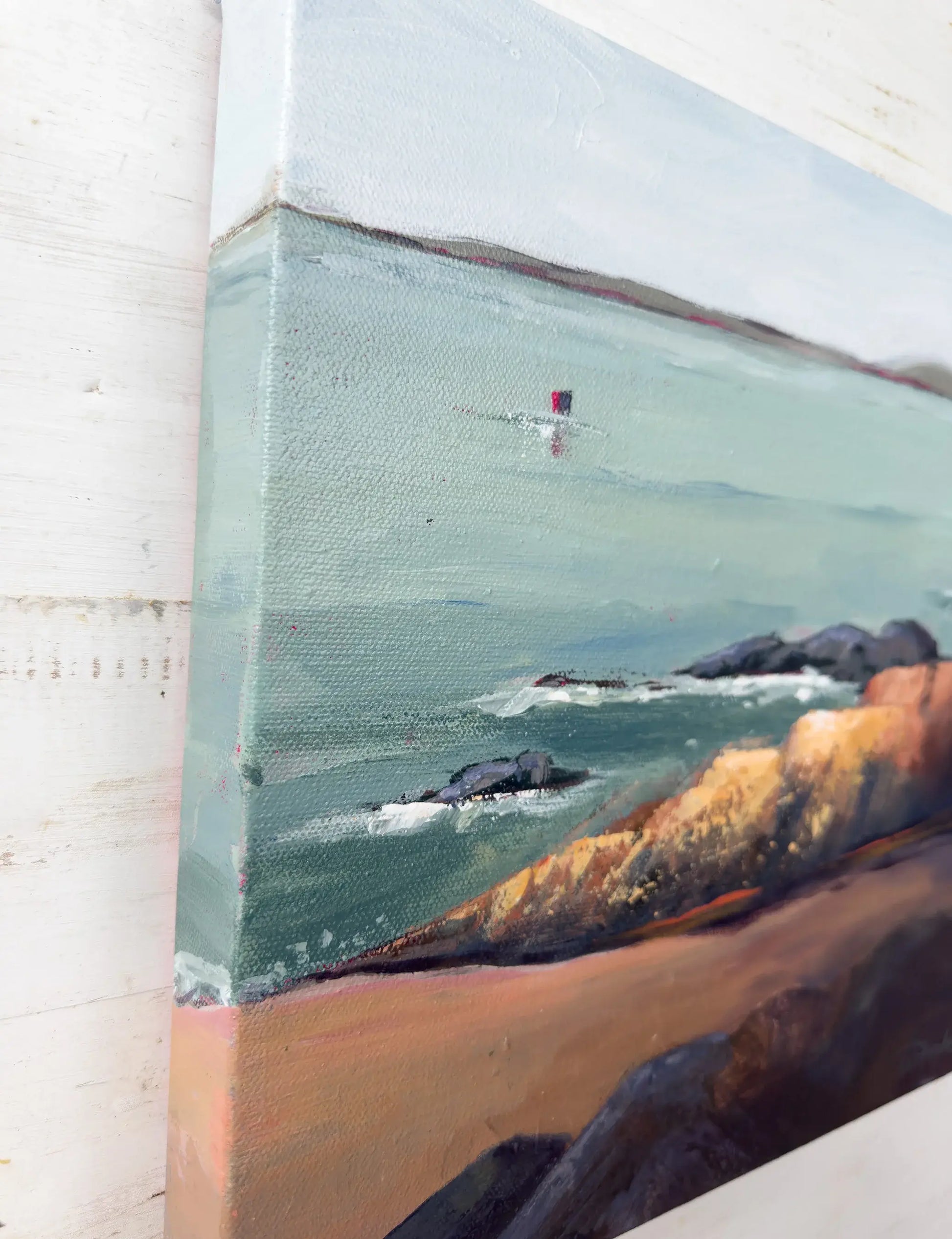 Close-up of a painting of a coastal scene with rocks and water. Original artwork titled "Rock" by Teri Stephens.