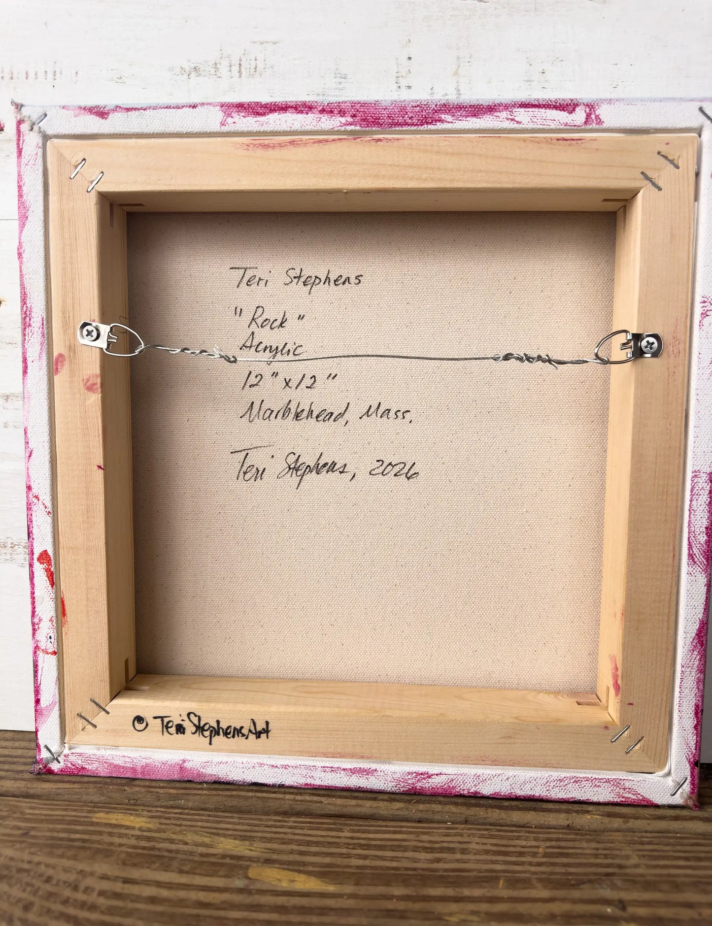 Back of a framed artwork with signature and details on a wooden surface, Original artwork titled "Rock" by Teri Stephens.