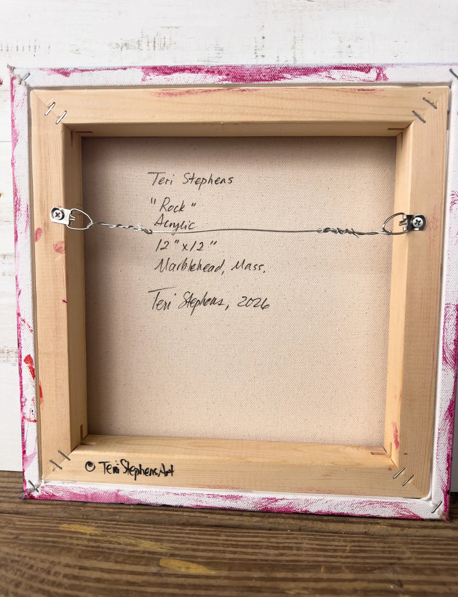 Back of a framed artwork with signature and details on a wooden surface, Original artwork titled "Rock" by Teri Stephens.