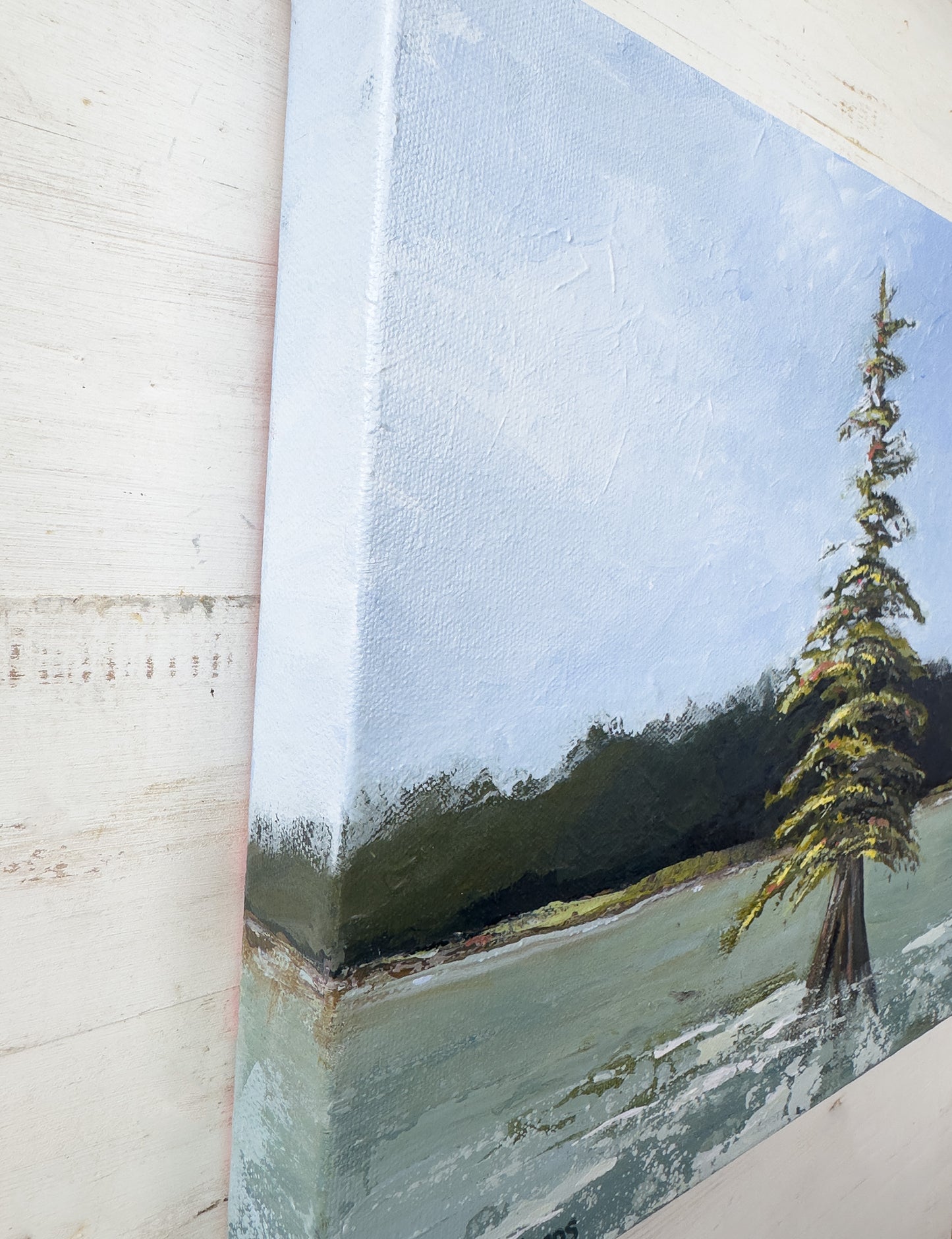 Close-up of a landscape painting with a tree on a textured wall. Angled view of "Stand" by Teri Stephens