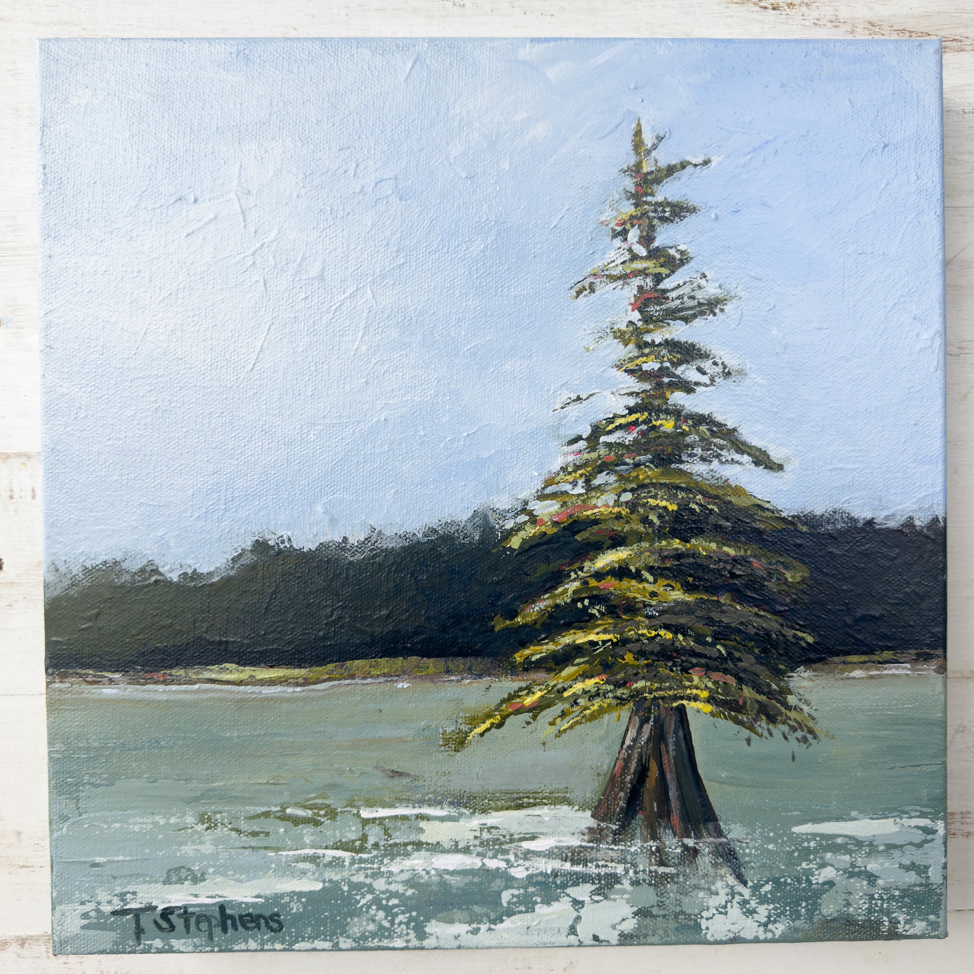 Painting of a solitary tree by a body of water with a blue sky. "Stand" by Teri Stephens