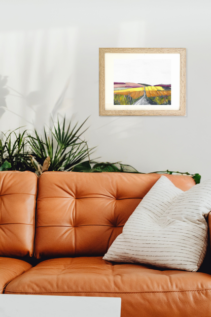 Framed artwork, titled "Turf" by Tennessee artist Teri Stephens, above an orange leather sofa with a plant in the background